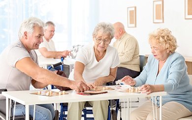 Drei Senioren spielen gemeinsam an einem hellen Tisch ein Gesellschaftsspiel mit Holzsteinen.
